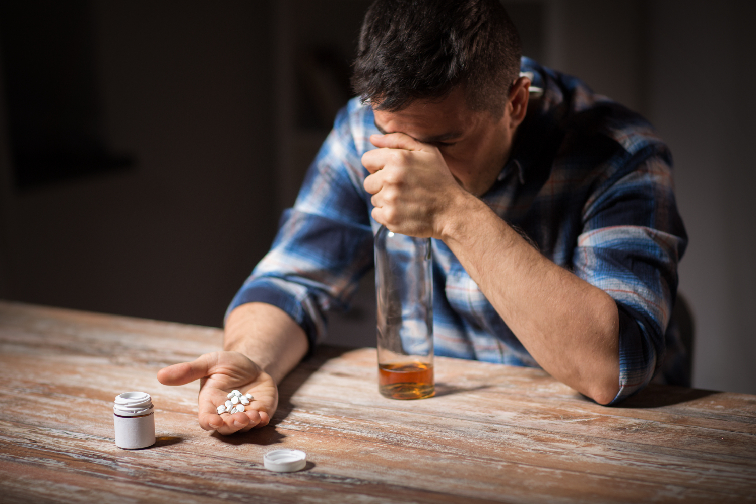Man holding pills and a bottle of alcohol, depicting the impact of substance abuse, relevant to Arizona law and personal injury.