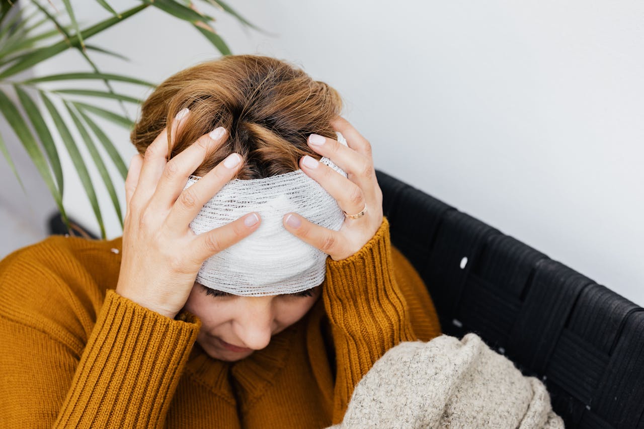 Woman with a head injury, holding her head in distress, illustrating symptoms after an accident in Arizona.