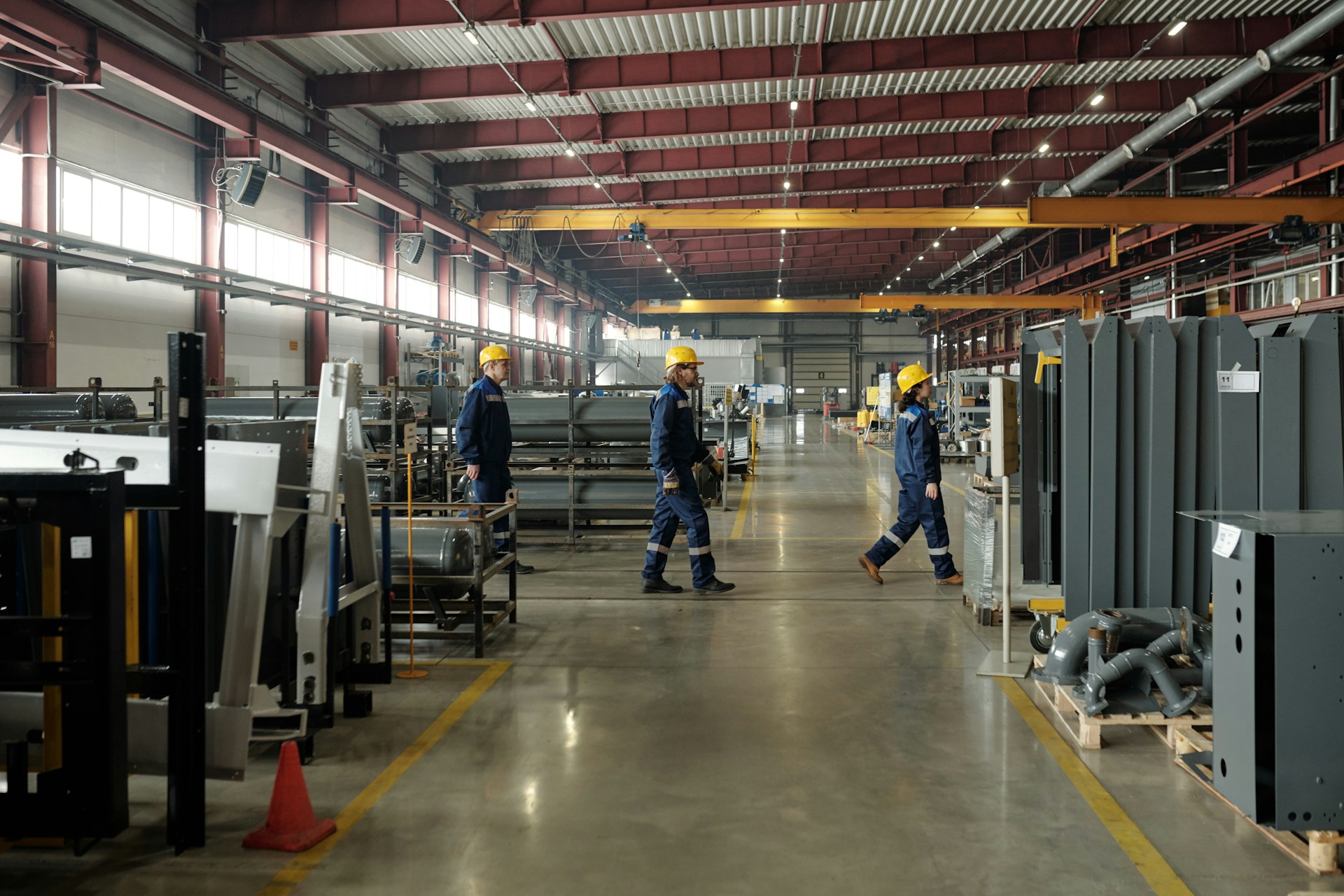 Workers in safety helmets walking through a spacious industrial warehouse in Arizona, emphasizing workplace safety and environment.