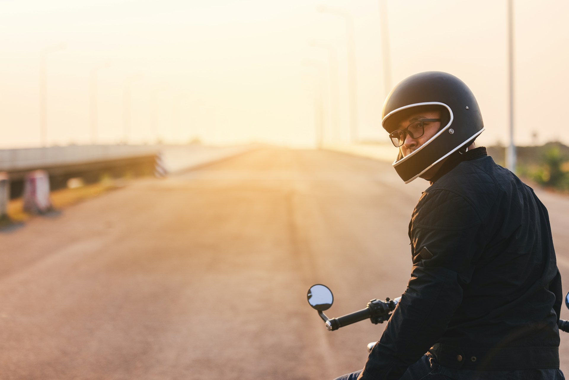 Managing the Aftermath of a Motorcycle Accident in Arizona Motorcyclist wearing a helmet on a road at sunset, representing motorcycle accident awareness in Mesa, Arizona.
