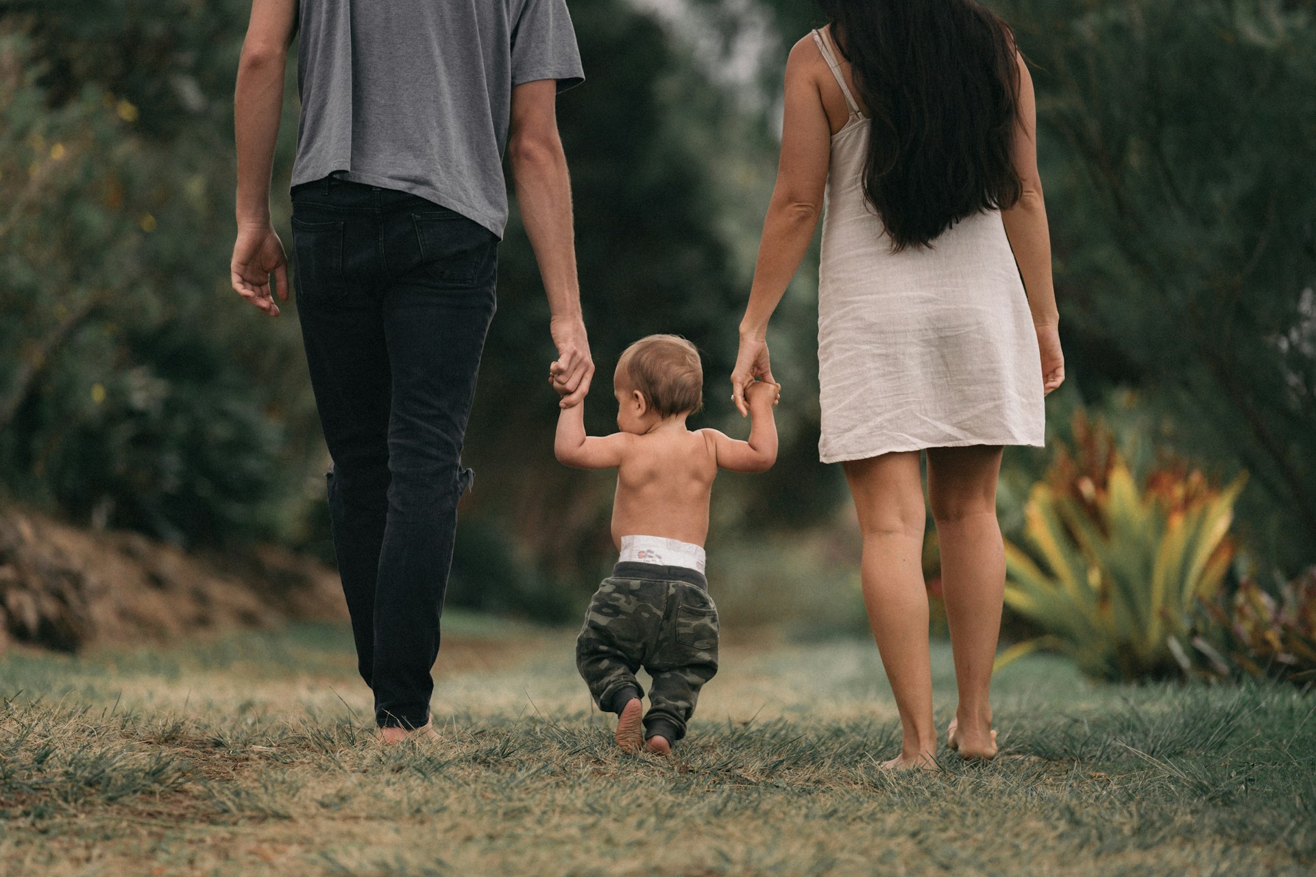 Family walking together in a park, emphasizing child custody matters in Arizona, with parents guiding their toddler.