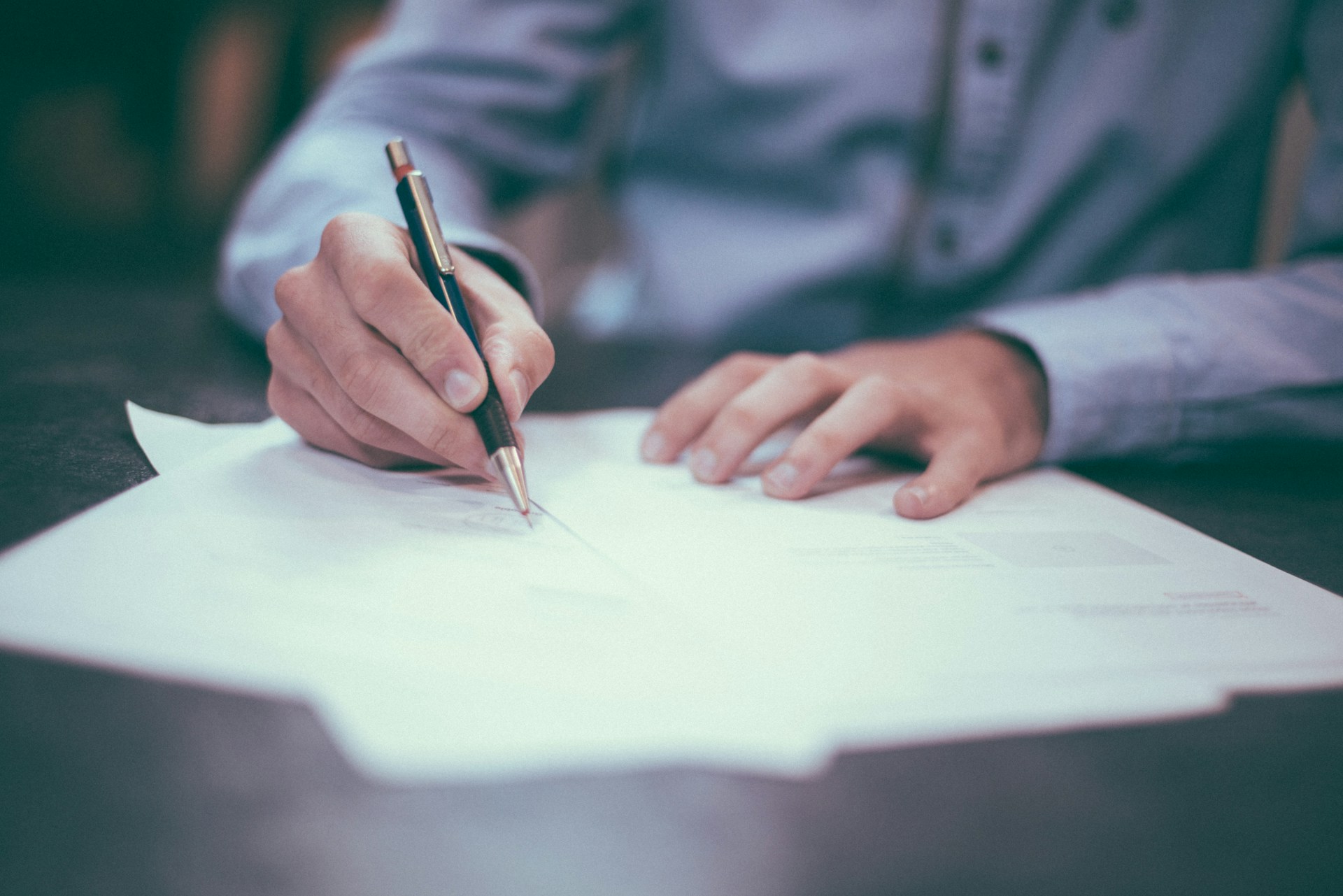 Person signing legal documents during consultation at Rowley Chapman Barney law firm in Mesa, Arizona.