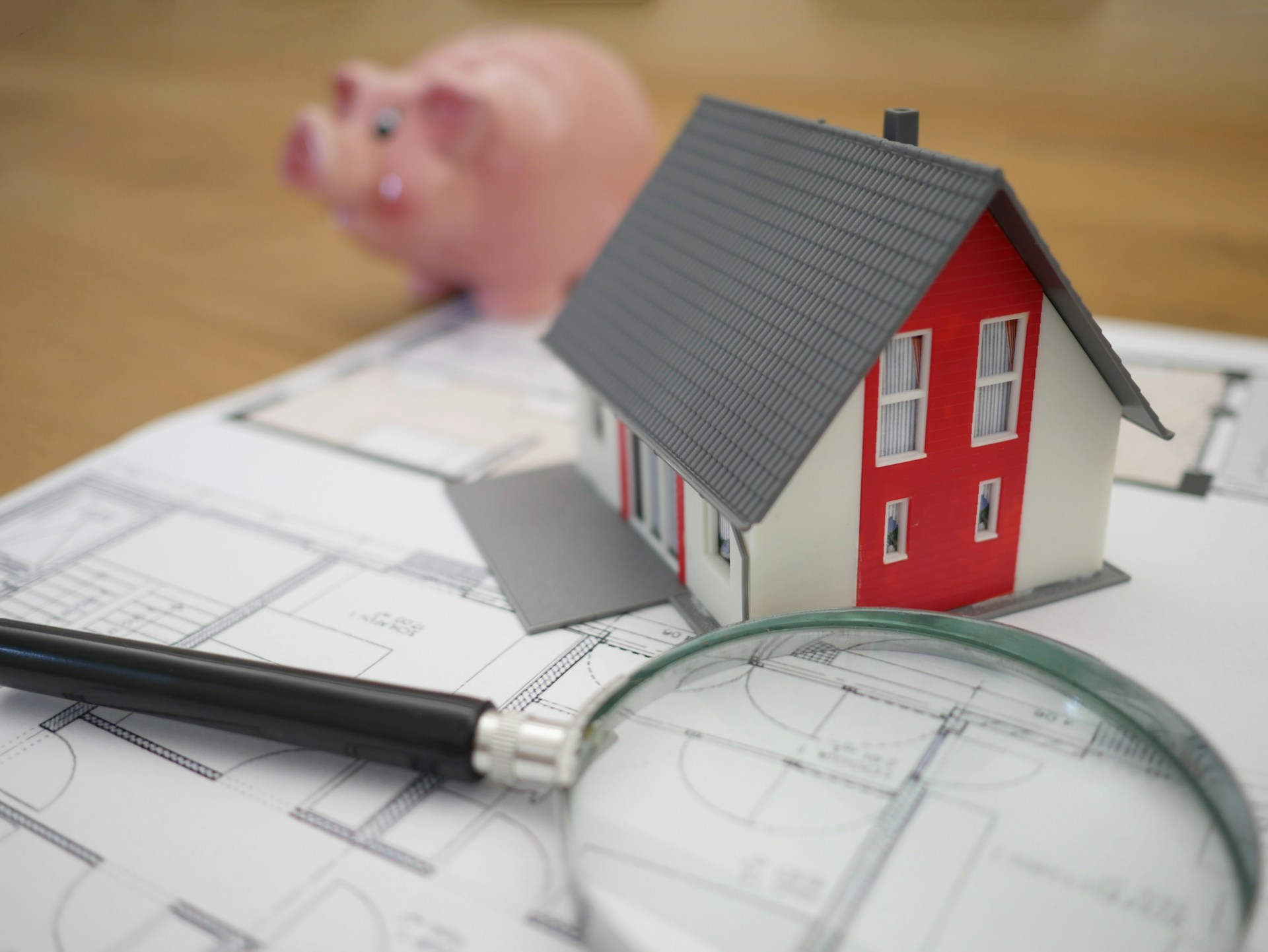 Navigating Complex Estate Planning Situations in Chandler Model house and magnifying glass on architectural plans with piggy bank, symbolizing estate planning in Mesa, Arizona.
