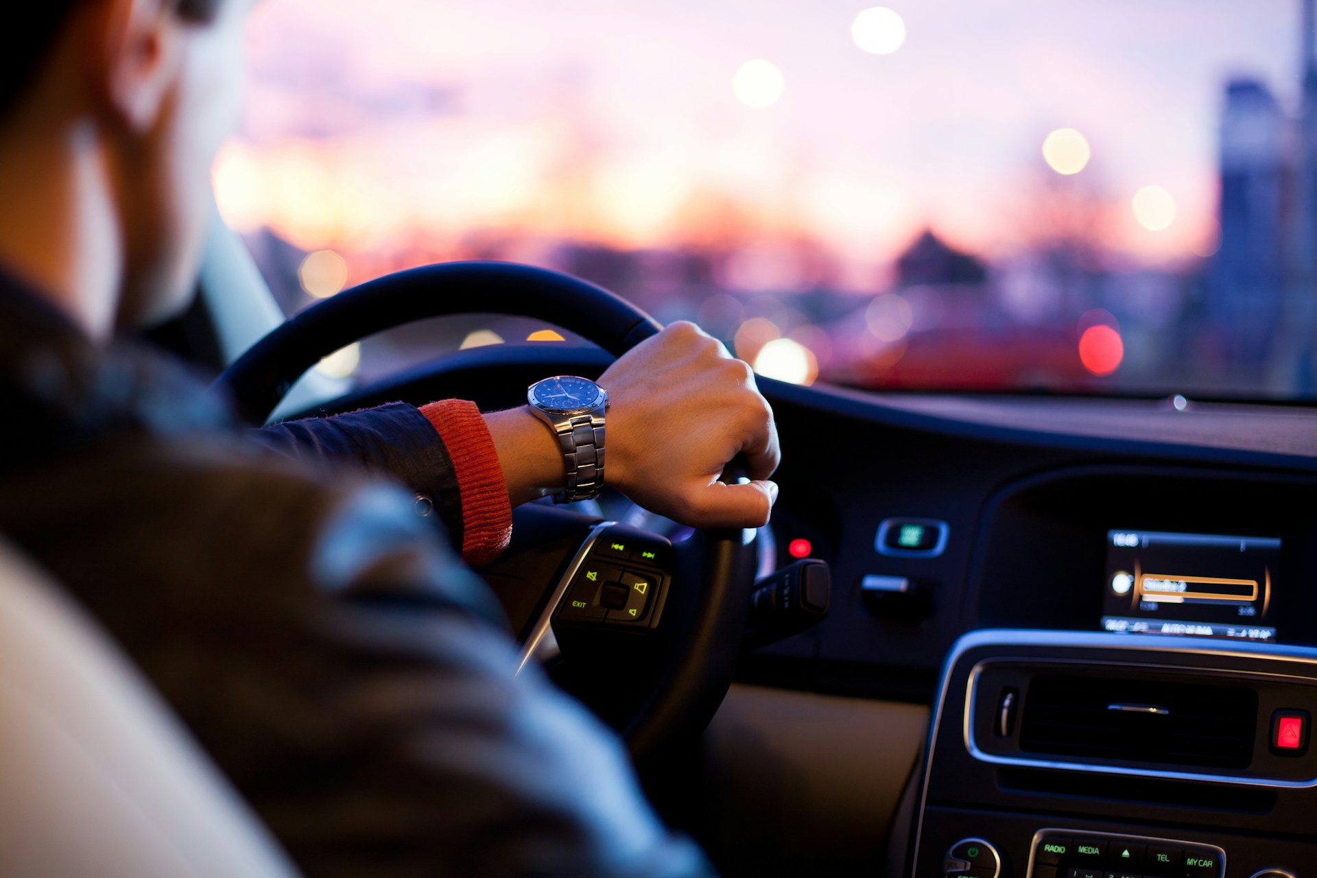 Driver holding steering wheel in car during dusk, representing car accidents and personal injury in Arizona.