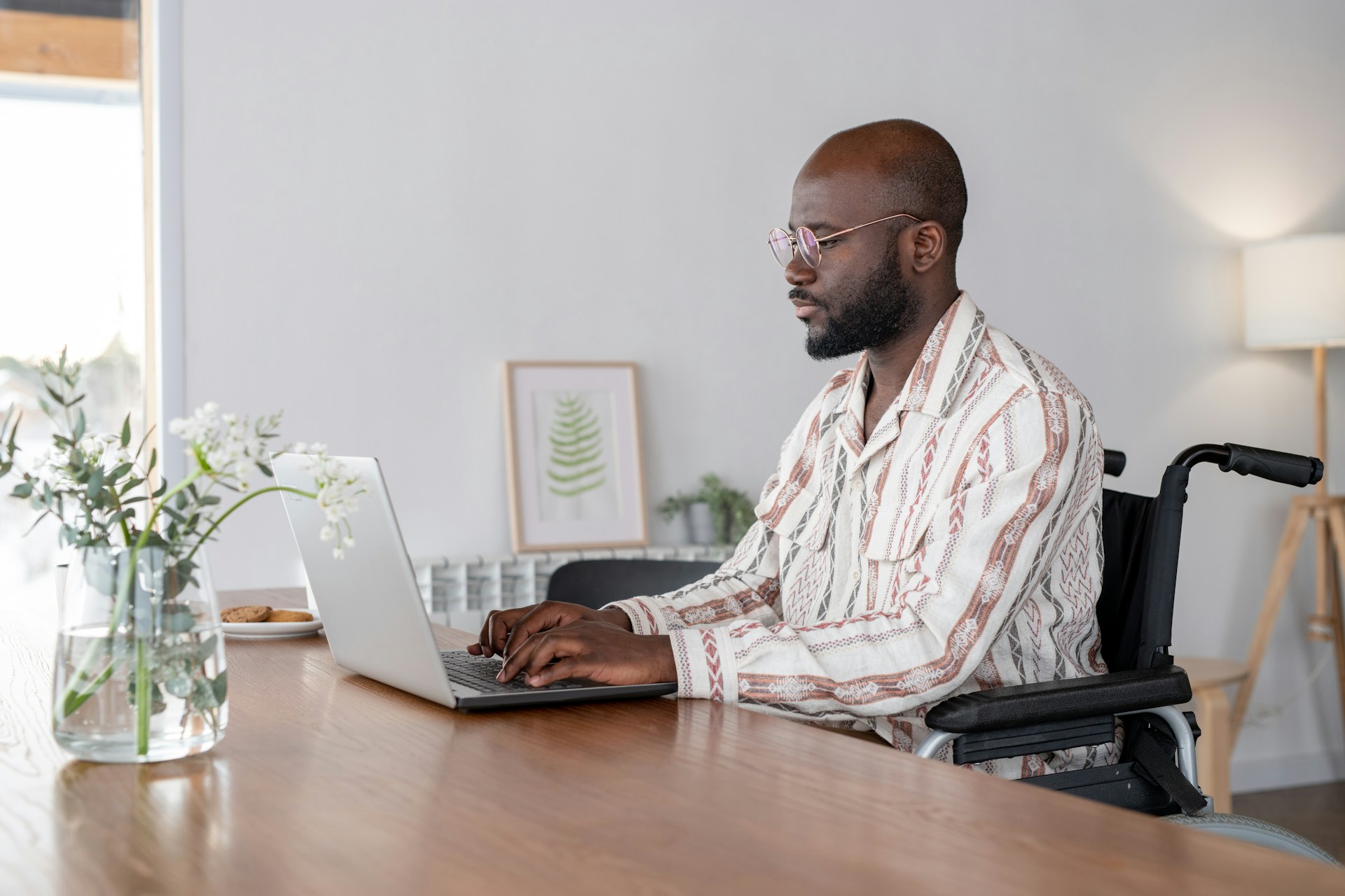 The Benefits of a Revocable Living Trust in Arizona Man in wheelchair using laptop at a desk in a modern office setting, reflecting legal consultation in Mesa, Arizona.
