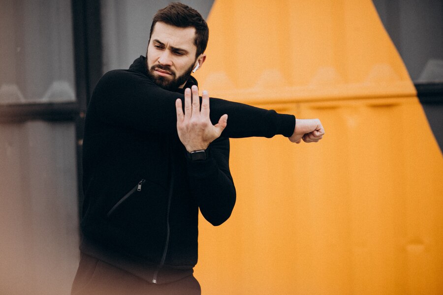 Man stretching his arm outdoors, demonstrating self-defense readiness, with an urban backdrop, relevant to Arizona self-defense laws.