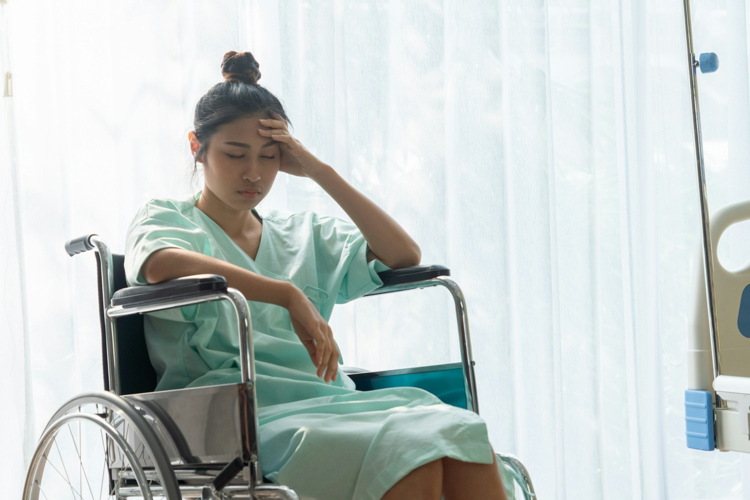 Woman in hospital gown sitting in wheelchair, showing signs of distress, related to personal injury legal issues in Arizona.