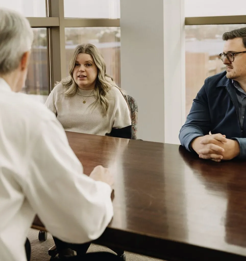 Three people engaged in a discussion at a conference table.